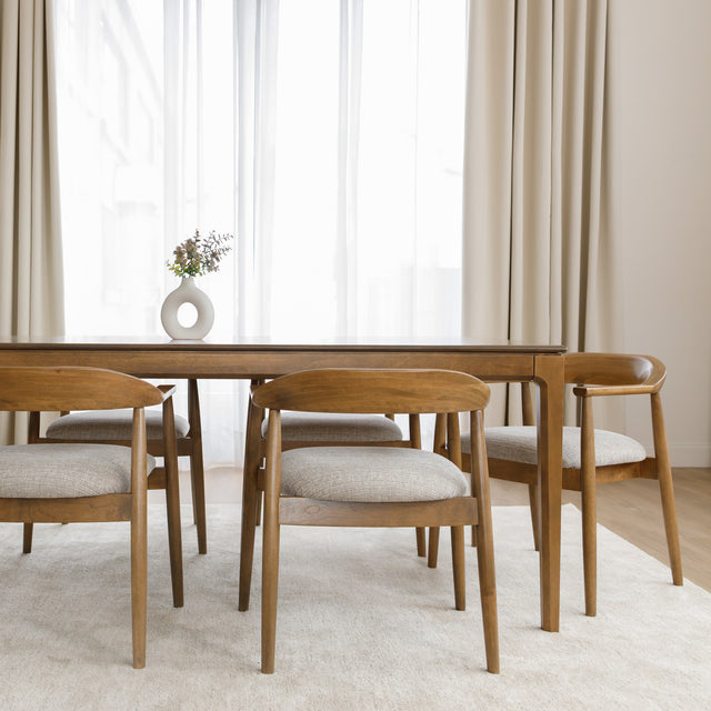 Table de cuisine en bois avec chaises rembourrées dans un intérieur minimaliste lumineux.