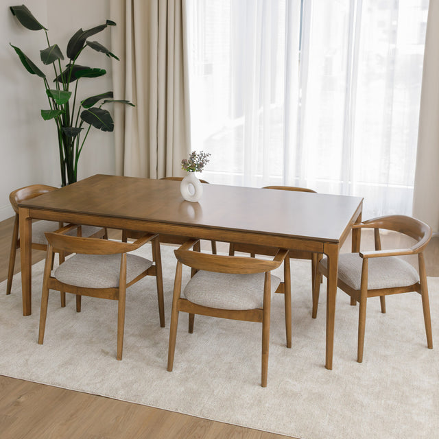 Table de cuisine en bois avec chaises rembourrées dans un intérieur minimaliste lumineux.