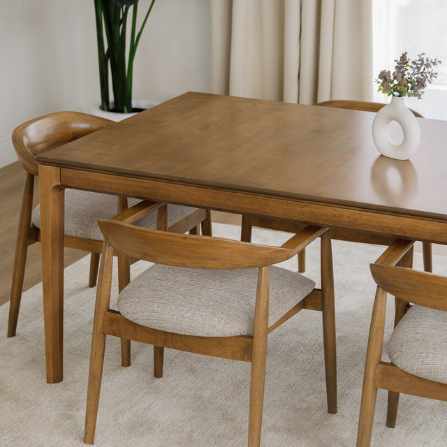 Table de cuisine en bois avec chaises rembourrées dans un intérieur minimaliste lumineux.
