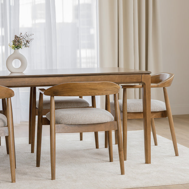 Table de cuisine en bois avec chaises rembourrées dans un intérieur minimaliste lumineux.