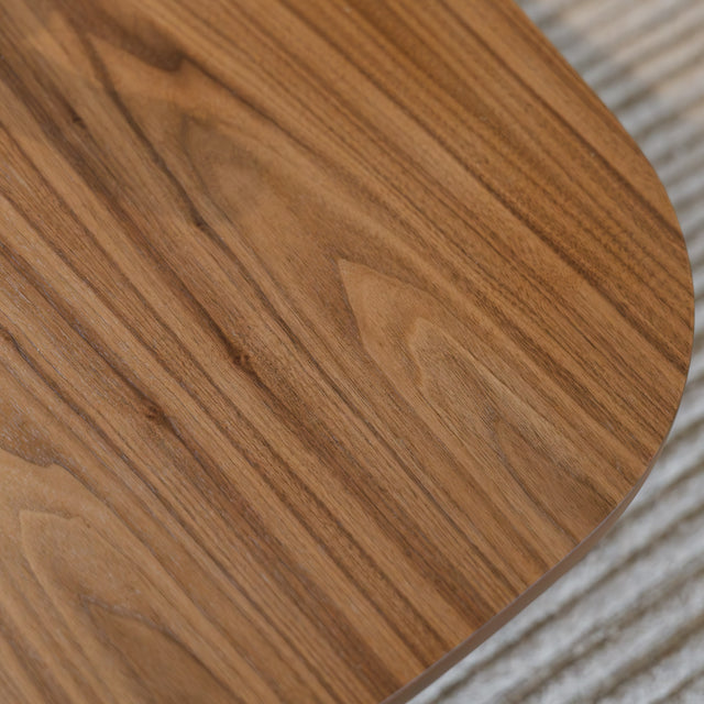Table basse ovale en bois noyer dans un salon moderne avec un canapé beige.