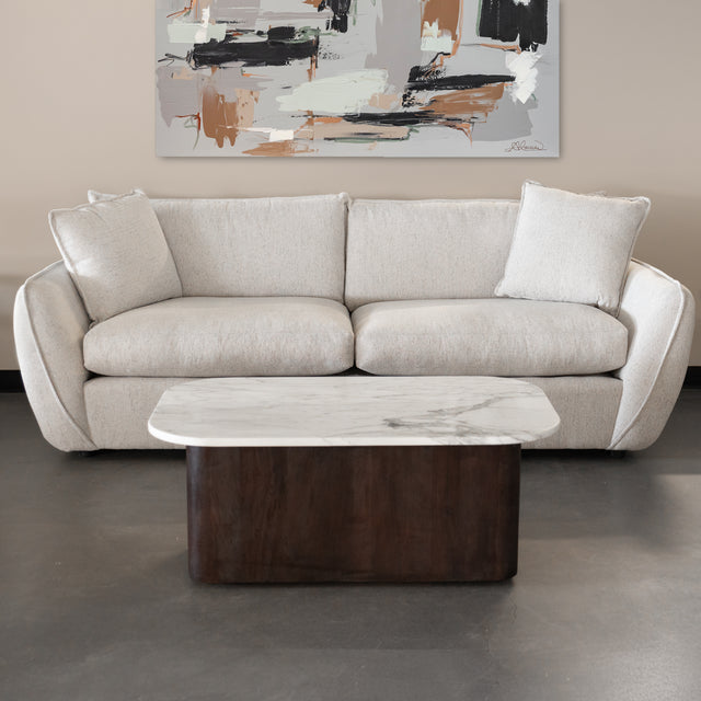 canape beige clair en tissu avec coussins moelleux et table basse en marbre et bois.