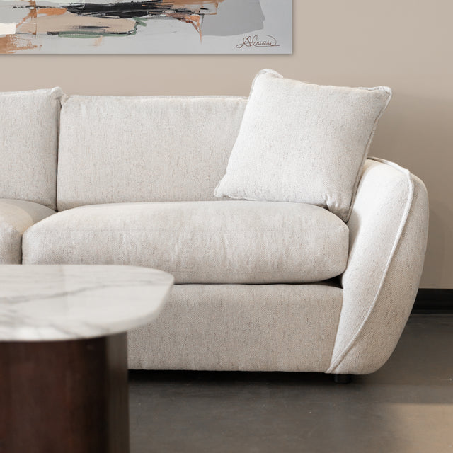 detail du canape beige clair en tissu avec coussin assorti et table basse en marbre.