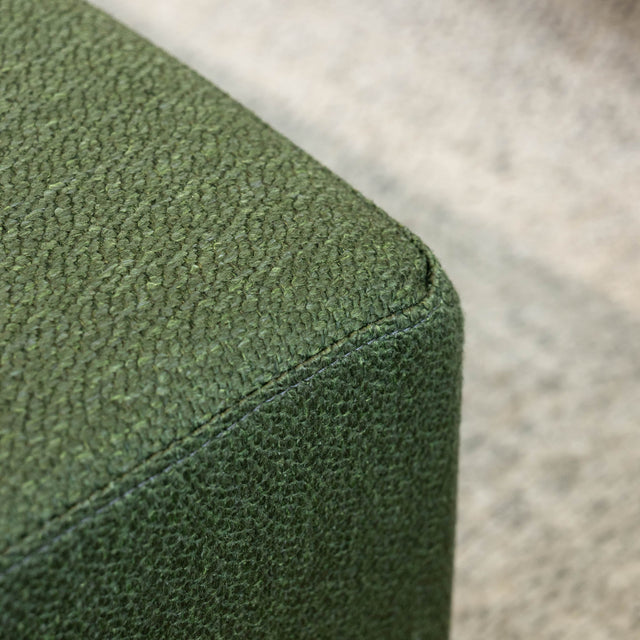 Détail ottoman carré vert en tissu texturé, finition soignée et angle net pour salon moderne.