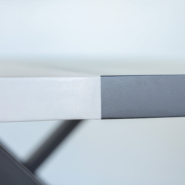 Table à manger moderne avec plateau béton ciment, tranche de frêne noir et piètement en métal noir, idéale pour salle à manger contemporaine.