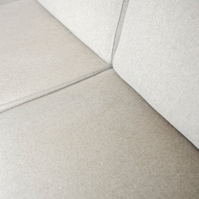 Image rapprochée d'un Sectionnel en tissu greige avec pattes noires, design moderne et assises confortables pour salon contemporain.