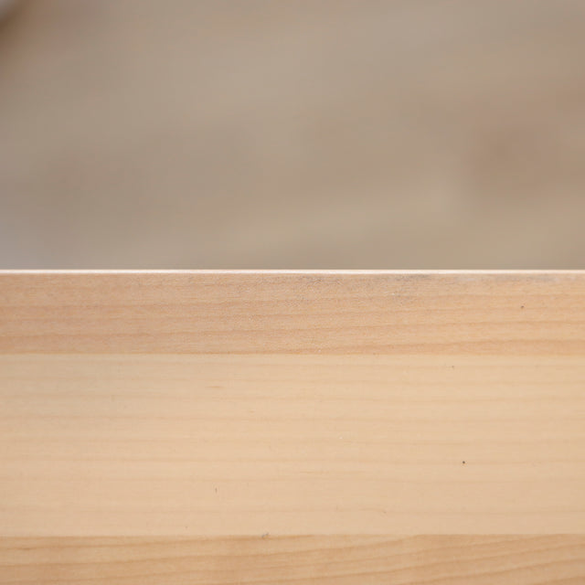 Image rapprochée d'une table rectangulaire en bois clair avec pieds en metal noir en X, design industriel elegant.