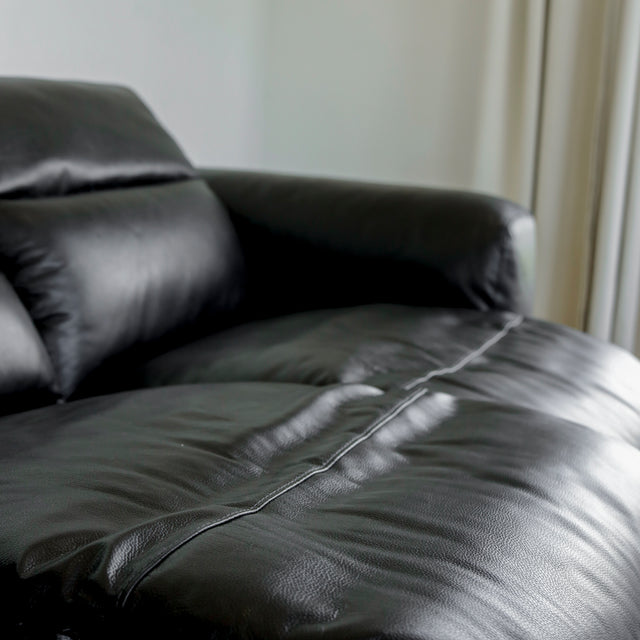zoom sur l assise en cuir noir du canape mettant en valeur les coutures et le fini lisse.