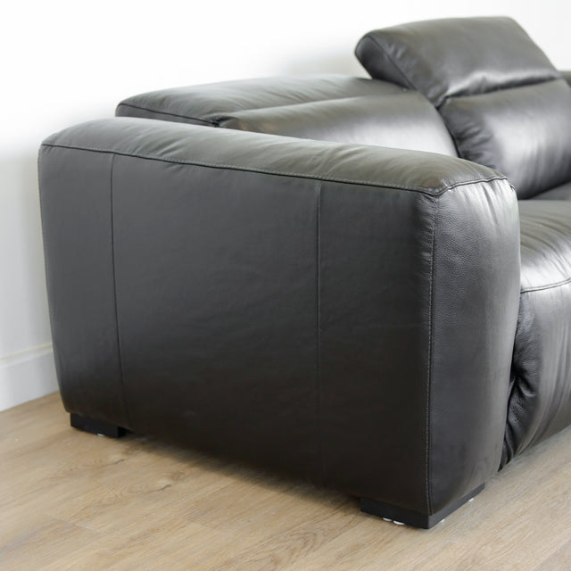 vue laterale du canape en cuir noir avec accoudoir epais et finition lisse elegante.