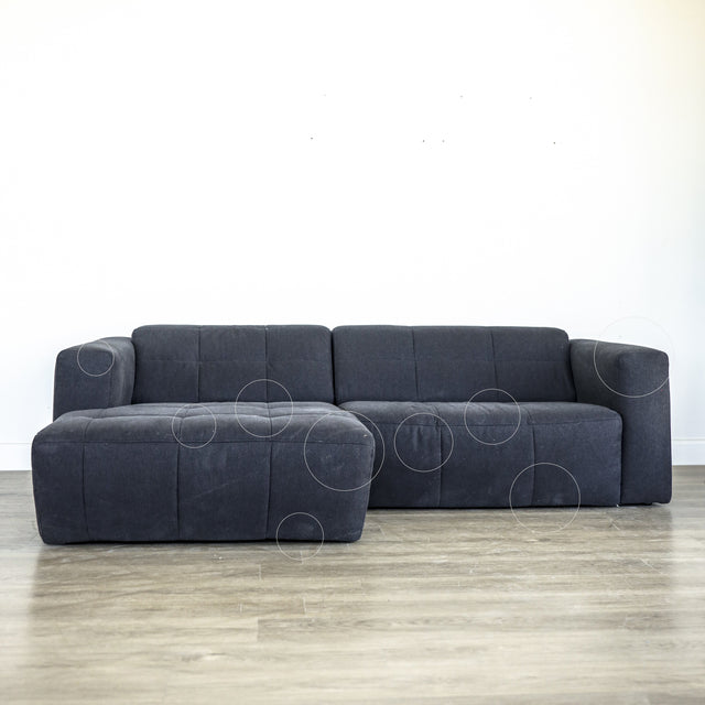 Canape d angle gris fonce matelasse au design moderne et lignes epurees.