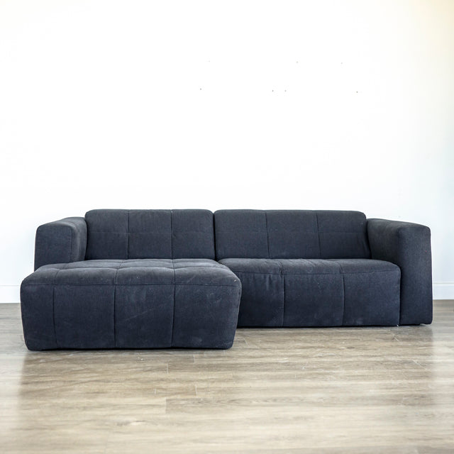 Canape d angle gris fonce matelasse au design moderne et lignes epurees.