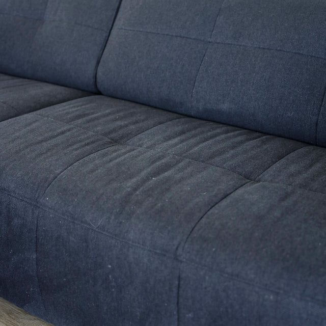 Detail de l assise du canape gris fonce matelasse au tissu doux et moderne.