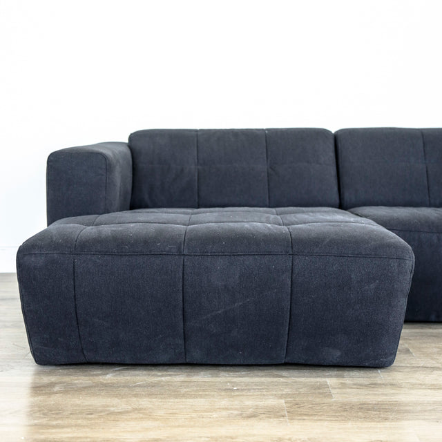 Canape d angle gris fonce matelasse au design moderne et lignes epurees.