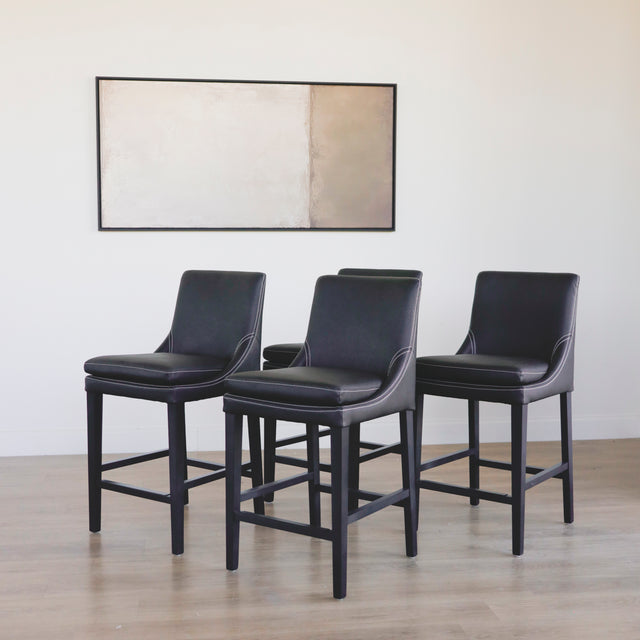 ensemble de tabourets comptoir en cuir végane noir avec coutures blanches et pieds en bois sombre.