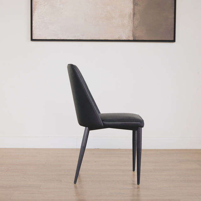 chaise moderne en simili cuir noir avec dossier a coutures horizontales et pieds en metal.