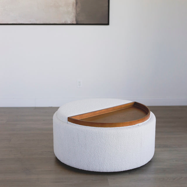 ottoman rond en tissu blanc bouclé avec plateau en bois amovible sur sol en bois.