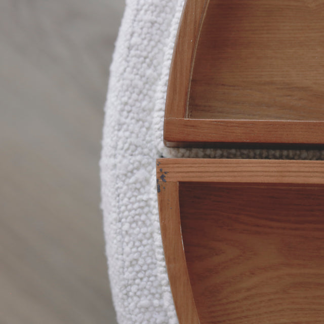 image rapprochée d'un ottoman en tissu blanc bouclé avec plateau amovible en bois noyer.