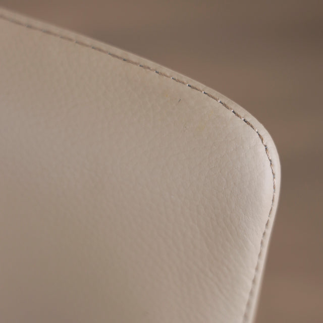 Image rapprochée du cuir d'un ensemble de deux chaises en cuir beige avec pattes en bois teinture noyer