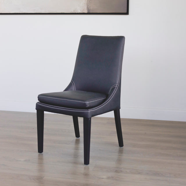 chaise moderne en cuir noir avec coutures blanches et pieds en bois sombre.