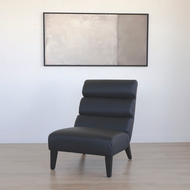 Fauteuil moderne en cuir noir avec dossier capitonne et pieds en bois fonce.