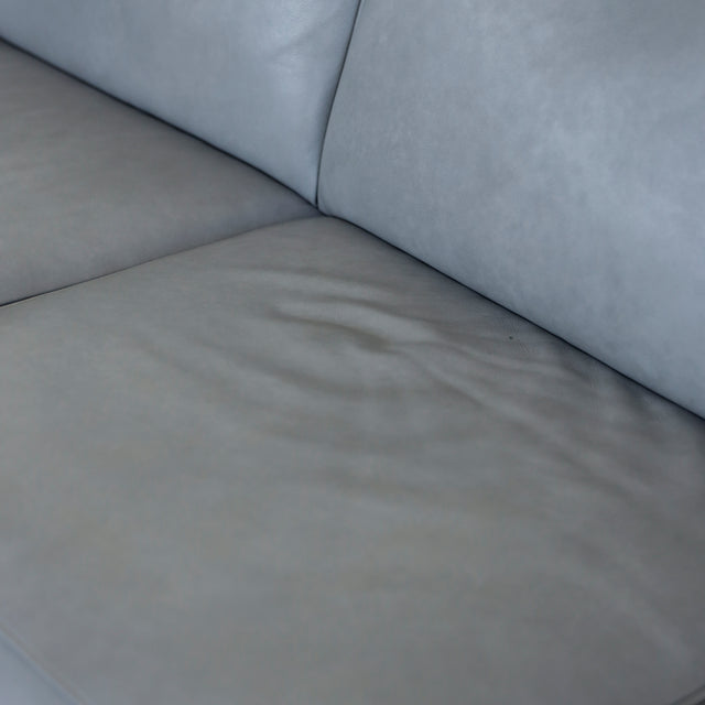 Image rapprochée d'un Canape avec chaise longue droite en cuir gris clair avec pieds noirs.