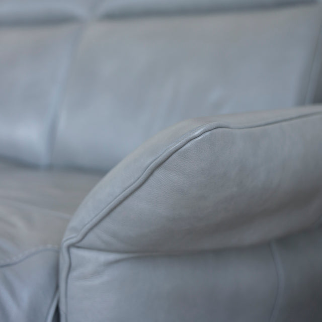 Image rapprochée d'un Canape avec chaise longue droite en cuir gris clair avec pieds noirs.