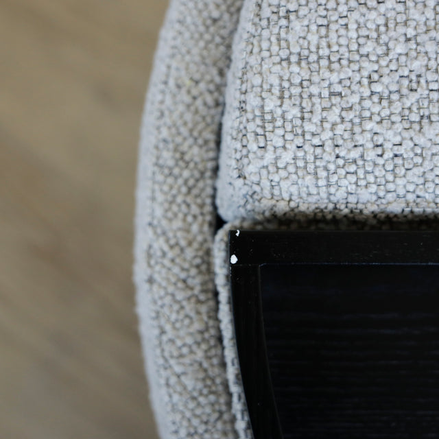 Image rapprochée d'un Pouf rond en tissu bouclé gris avec plateau noir amovible sur sol en bois clair.