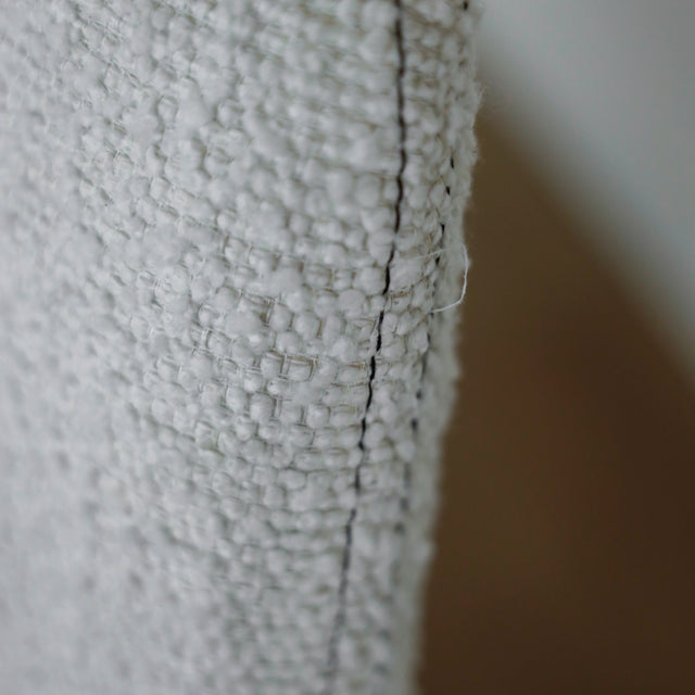 image rapprochée d'un ensemble de chaises modernes en tissu bouclé ivoire avec pieds en bois pâle avec défaut d'un fil tiré.