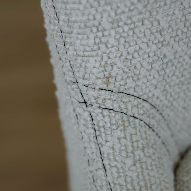 image rapprochée d'un ensemble de chaises modernes en tissu bouclé ivoire avec pieds en bois pâle avec défaut d'une tache.