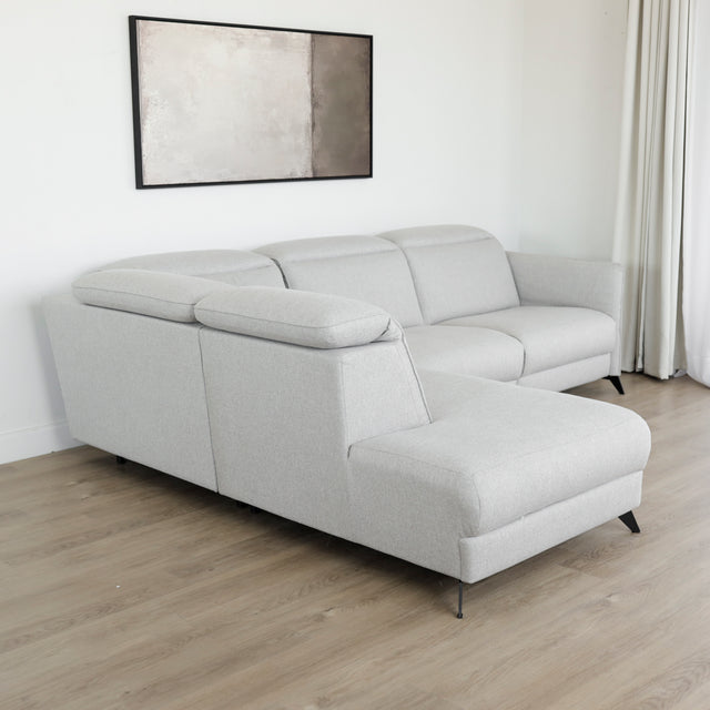 Modulaire inclinable moderne en tissu gris clair avec pieds metalliques noirs sur parquet clair.