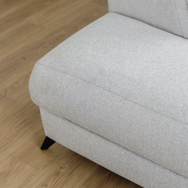 Modulaire inclinable moderne en tissu gris clair avec pieds metalliques noirs sur parquet clair.