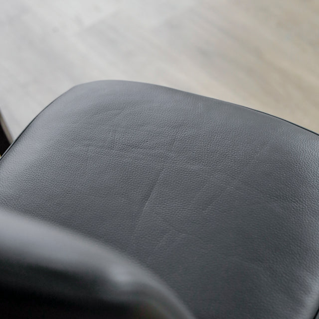 image rapprochée d'un ensemble de six chaises modernes en cuir noir avec pieds en bois noir sur parquet clair.