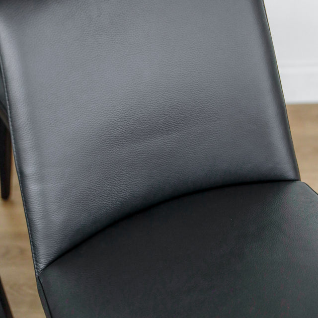 image rapprochée d'un ensemble de six chaises modernes en cuir noir avec pieds en bois noir sur parquet clair.