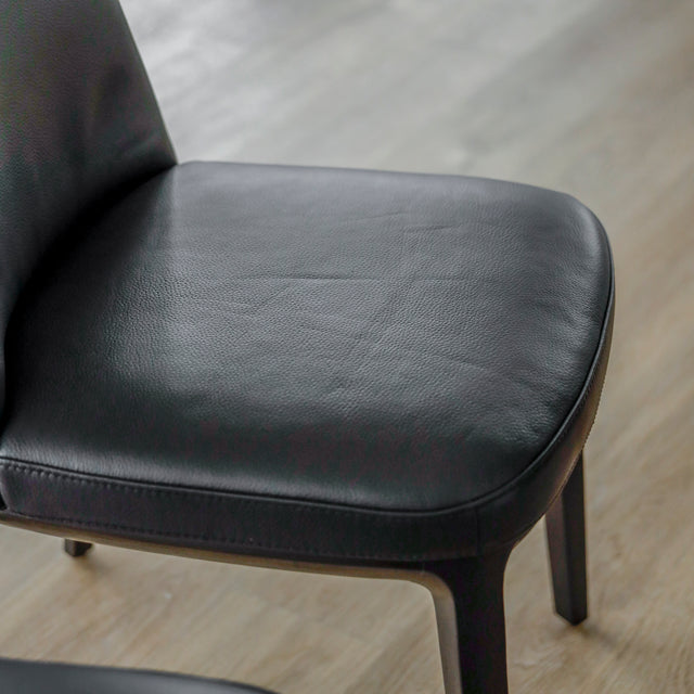 image rapprochée d'un ensemble de six chaises modernes en cuir noir avec pieds en bois noir sur parquet clair.