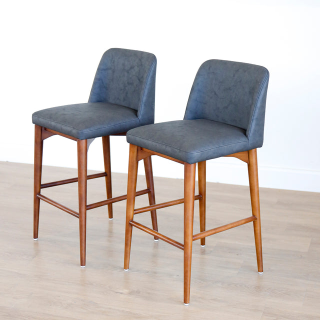 Deux tabourets de comptoir en cuir végane noir avec pieds en bois noyer, style moderne pour cuisine ou salon.