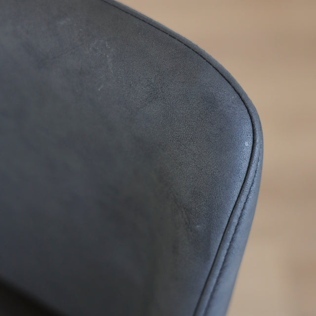 Image rapprochée d'un tabouret de comptoir en cuir végane noir avec pieds en bois noyer, style moderne pour cuisine ou salon.