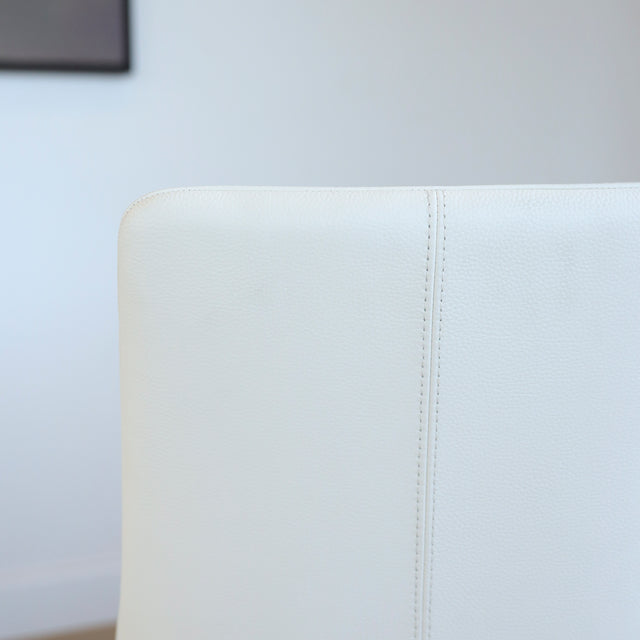 Image rapprochée d'une chaise moderne en cuir blanc avec pieds en bois couleur noyer, design pure pour salle a manger contemporaine.