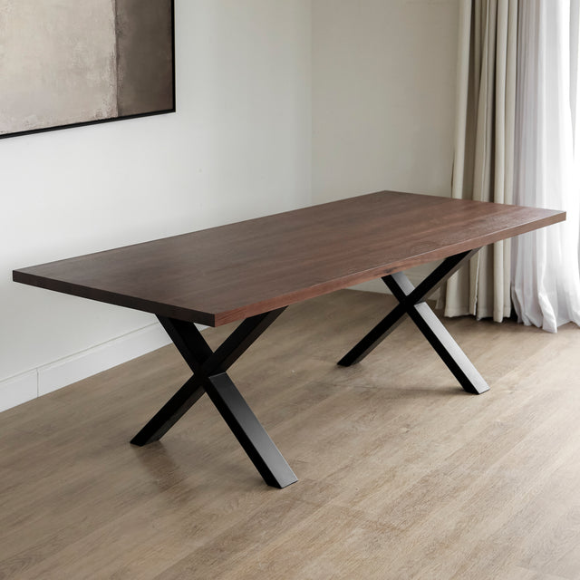 Table rectangulaire en bois fonce avec pieds en metal noir en X, style industriel contemporain.