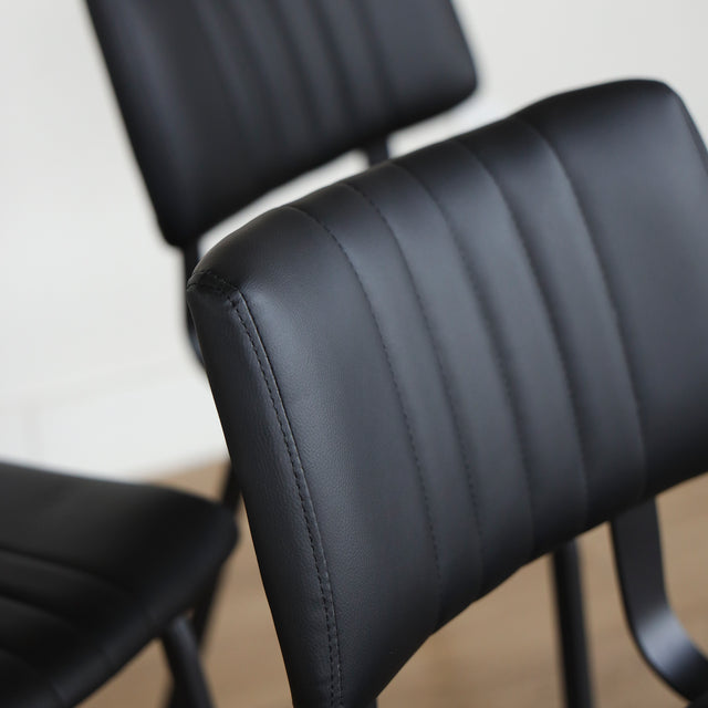 Quatre chaises noires en simili cuir avec pieds en metal, design moderne pour salle a manger.