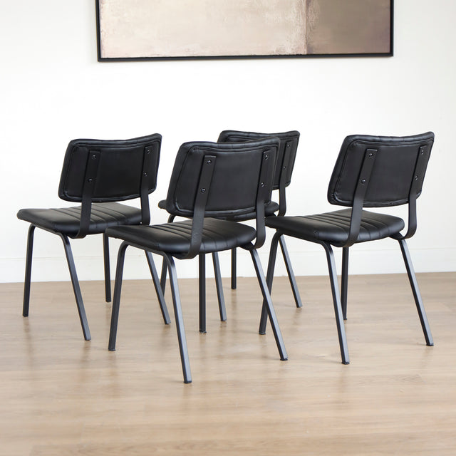 Quatre chaises noires en simili cuir avec pieds en metal, design moderne pour salle a manger.