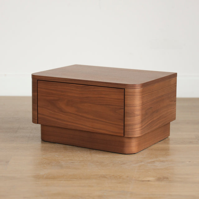Table de chevet moderne en bois noyer avec coins arrondis et tiroir integre.