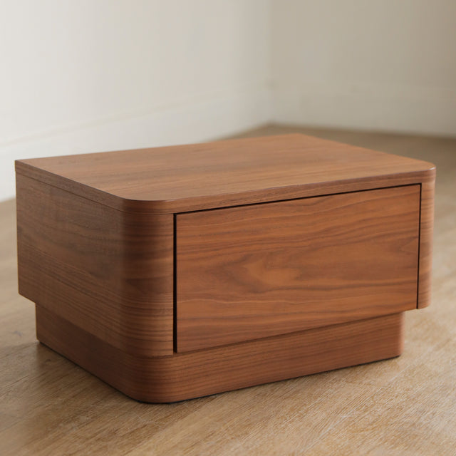 Table de chevet moderne en bois noyer avec coins arrondis et tiroir integre.
