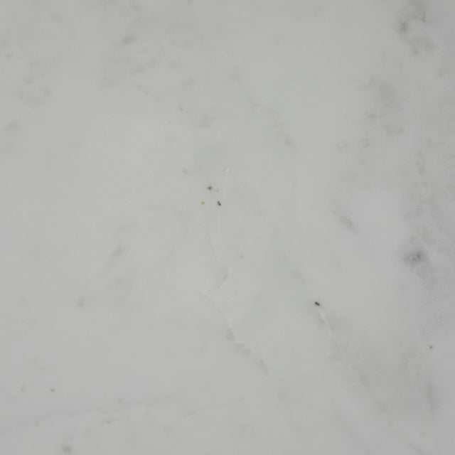 Image rapprochée d'une Table basse ronde avec plateau en marbre blanc et structure en metal noir, style moderne et minimaliste.