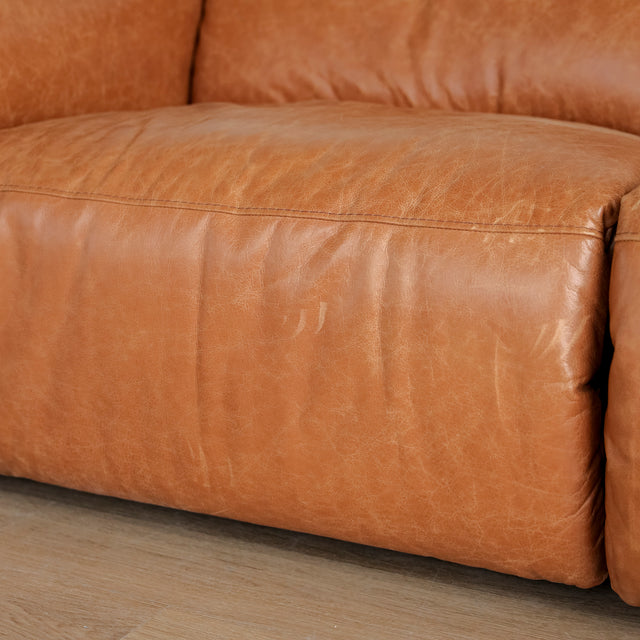 Image rapprochée d'un canape inclinable en cuir brandy au design contemporain avec accoudoirs larges et assises confortables.