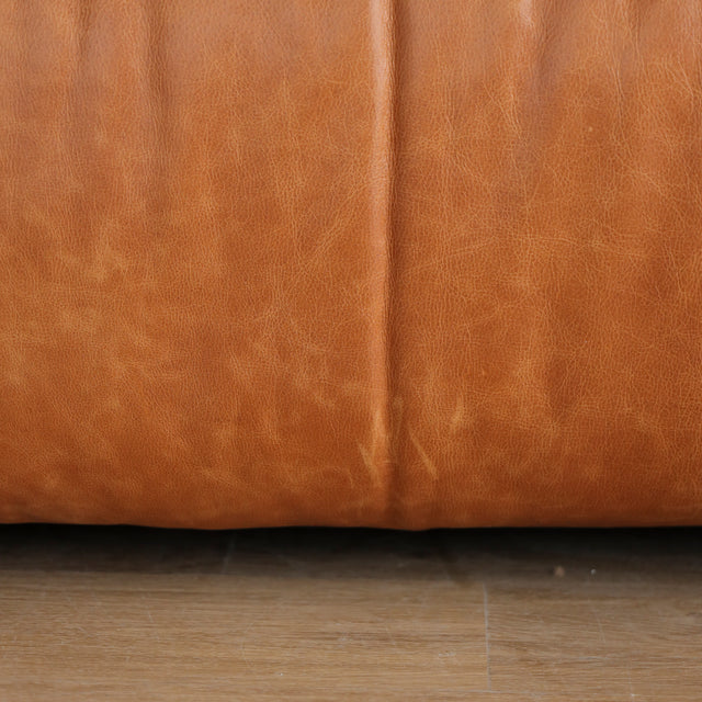 Image rapprochée d'un canape inclinable en cuir brandy au design contemporain avec accoudoirs larges et assises confortables.