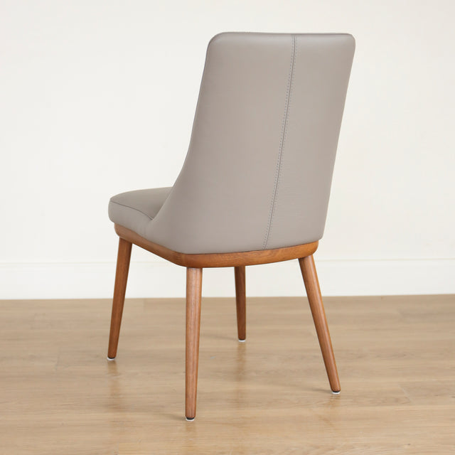 Chaise moderne en cuir gris avec assise rembourree et pieds en bois.