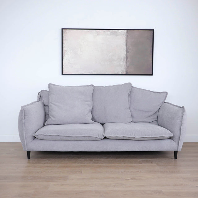 Canapé gris moderne avec coussins moelleux dans un salon minimaliste.