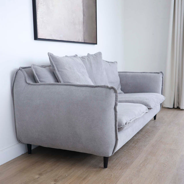 Canapé gris moderne avec coussins moelleux dans un salon minimaliste.