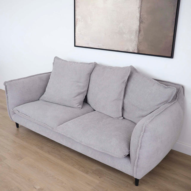 Canapé gris moderne avec coussins moelleux dans un salon minimaliste.