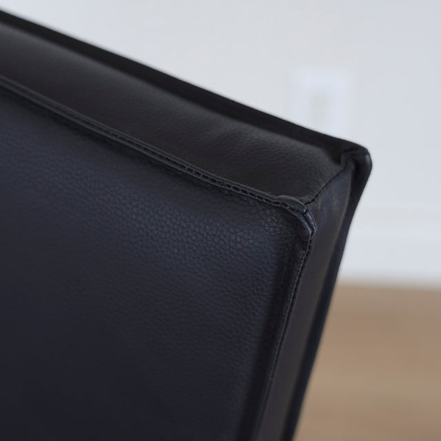 image rapprochée chaise noire avec assise rembourree et structure en bois naturel.